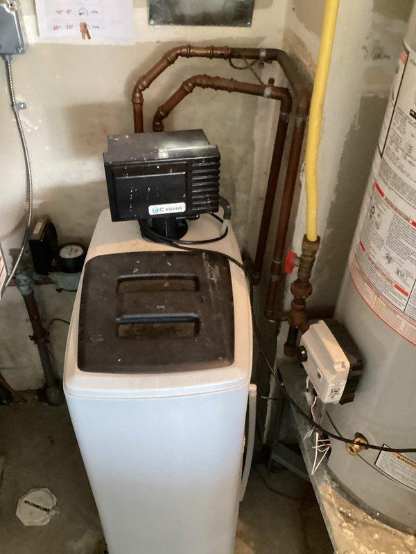 Conducted on-site evaluation of existing water treatment system in residential utility room. Assessed current water softener unit with SCOWATER control head and existing copper piping configuration, documented equipment condition, and provided comprehensive estimate for new water softener installation to replace aging system.