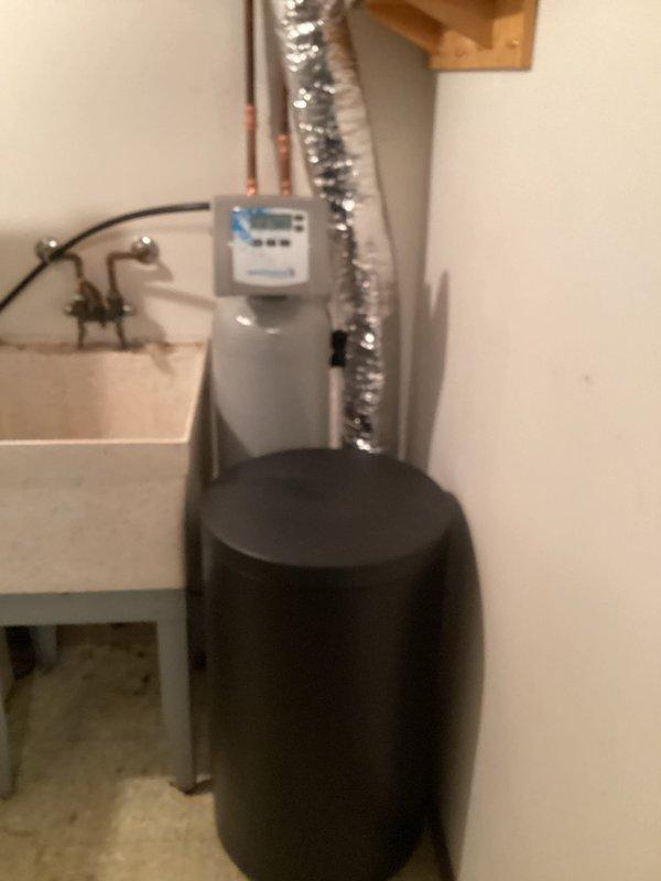 Installed Water Right Impression series water softener system in utility room, completing all necessary plumbing connections with copper piping and integrating the unit with existing water heater infrastructure. The installation included mounting the digital control unit, establishing proper drainage, and ensuring all connections meet code requirements for optimal water treatment performance.