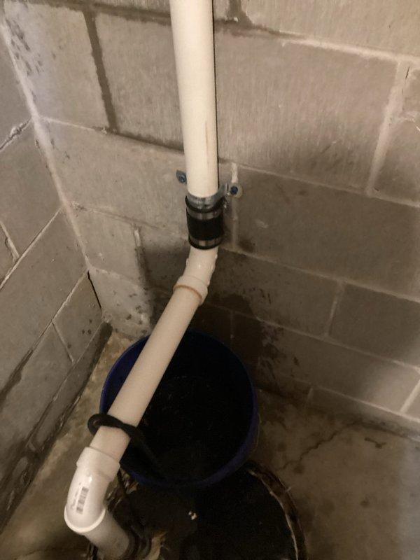 Responded to a sump pump drainage system leak in basement utility area. Upon inspection, identified active leak at 90-degree PVC fitting connection on vertical discharge pipe. Removed compromised drain section and 90-degree elbow fitting. Installed new PVC pipe section and fitting, securing connection with rubber coupling. Tested system for proper drainage flow and verified all connections were watertight with no further leakage.