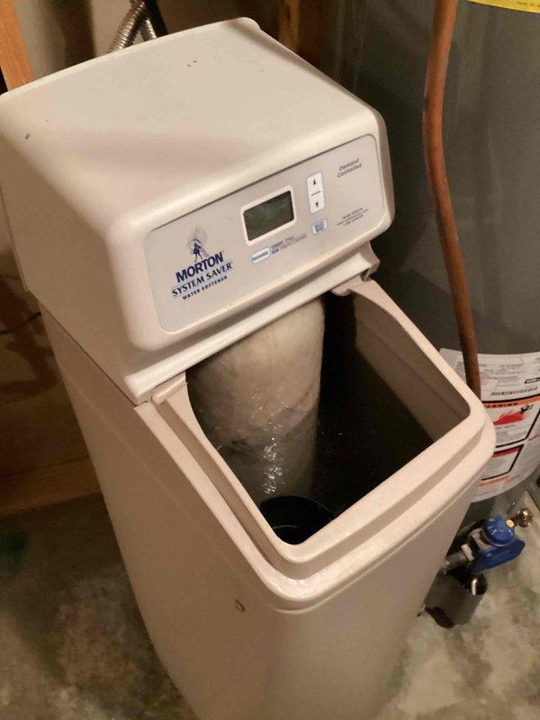 Responded to service call for Morton System Saver water softener continuously filling despite being unplugged from electrical outlet. Upon arrival, confirmed main water line had been shut off to prevent overflow. Conducted diagnostic assessment and determined softener was not entering regeneration cycle. Attempted manual regeneration through control panel, which failed to initiate. Verified mechanical and electrical failure of regeneration system. Documented existing installation with water heater and plumbing configuration. Provided estimate for complete water softener replacement due to non-functional regeneration components.