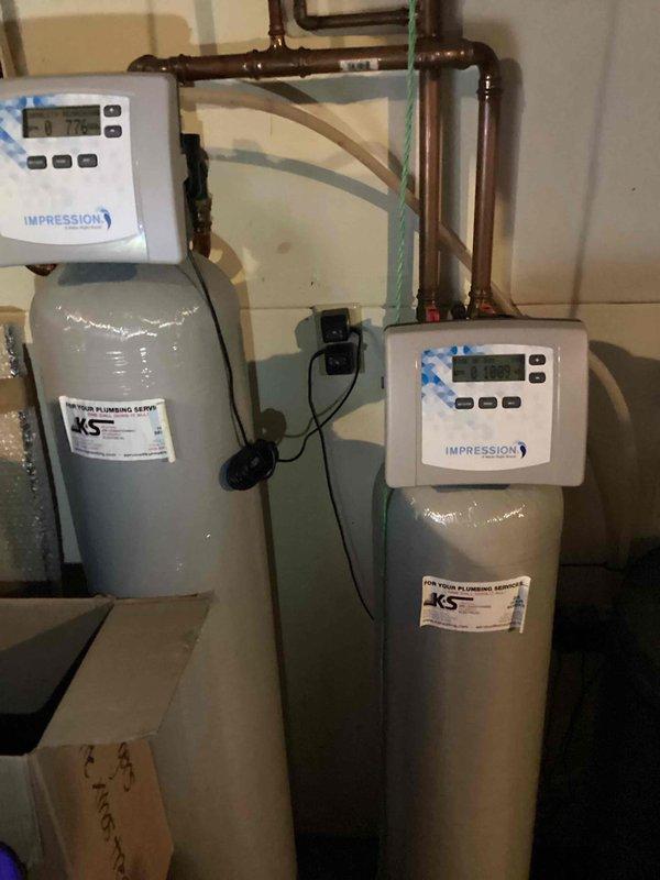 Responded to service call regarding water softener system not functioning properly, with customer reporting clothes not getting clean. Upon arrival, tested water hardness and confirmed reading of 7 ppm. Inspected dual-tank water treatment system consisting of water softener and iron filter with Impression digital control units. Adjusted and recalibrated settings on both the softener and iron filter to restore proper operation. Performed manual regeneration cycle on softener unit to verify system functionality. Retested water hardness to confirm proper treatment levels. System restored to full operational status with all components functioning correctly.
