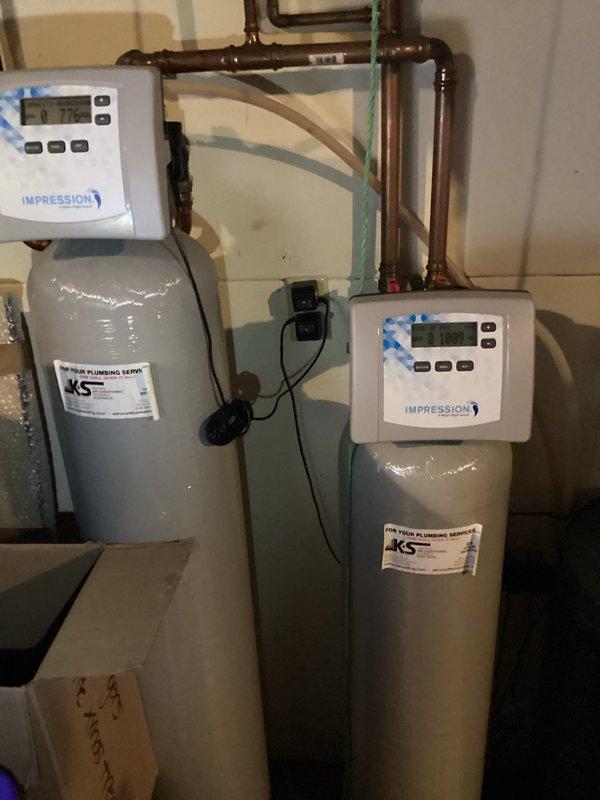 Responded to service call regarding water softener system not functioning properly, with customer reporting clothes not getting clean. Upon arrival, tested water hardness and confirmed reading of 7 ppm. Inspected dual-tank water treatment system consisting of water softener and iron filter with Impression digital control units. Adjusted and recalibrated settings on both the softener and iron filter to restore proper operation. Performed manual regeneration cycle on softener unit to verify system functionality. Retested water hardness to confirm proper treatment levels. System restored to full operational status with all components functioning correctly.
