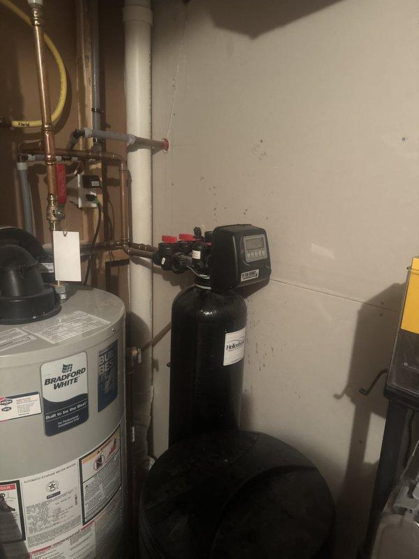 Responded to service call for water softener with brine tank continuously filling. Diagnosed faulty injector assembly causing improper brine draw and regeneration cycle malfunction. Removed and replaced defective red plastic injector component with new unit, restoring proper water softener operation and preventing brine tank overflow.