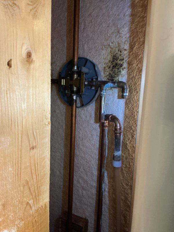 Responded to emergency call for burst pipe causing ceiling leak. Upon arrival, found water supply to house already shut off. Inspection revealed leak originating from hot water side where copper pipe connects to valve. Accessed plumbing through wall cavity to assess damage and source of leak. Capped the affected copper line to stop water intrusion and prevent further damage to ceiling and surrounding areas. Documented existing plumbing configuration including copper pipes, PEX connections, and valve assembly. Provided detailed estimate for permanent repair of the damaged hot water line and restoration of water service.