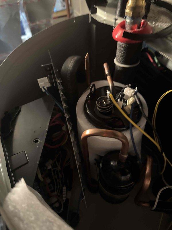 Responded to repeat service call for Bradford White heat pump water heater displaying FF error code related to air system malfunction. Upon inspection, diagnosed seized electronic expansion valve (EEV) preventing proper refrigerant flow through the heat pump system. Documented unit condition and component failure with photographs of internal compartment showing copper refrigerant lines, blower assembly, and electrical connections, as well as external view of unit with control panel and plumbing connections. Determined unit requires warranty replacement due to failed EEV component that cannot be freed or repaired in field conditions.