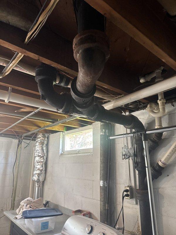 Responded to report of slow water leak in basement noticed by tenant after shower use. Conducted thorough inspection of exposed plumbing system including corroded cast iron pipes, white PVC drainage lines, and associated fixtures in utility area. Attempted to recreate leak conditions but unable to observe active water discharge or identify definitive source of reported moisture. Inspected ceiling-mounted piping, wall-mounted vertical runs, and connections near laundry appliances. No visible dripping, pooling, or wet areas detected during service visit. Documented existing plumbing conditions including significant rust and corrosion on older black iron piping system. Advised that leak may be intermittent or related to specific usage patterns. Possible callback may be required if leak reoccurs for further diagnostic evaluation.