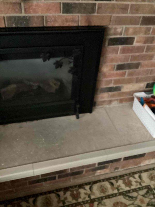 Responded to gas leak concern for fireplace insert with exterior gas line installation. Upon inspection, found flexible gas piping (CSST) with severely deteriorated yellow protective jacket exposing bare piping to potential corrosion and weather damage. The exterior-mounted gas line runs along building siding to supply interior brick fireplace with glass doors. Documented existing conditions with photographs showing compromised protective covering on exterior gas line routing. Provided estimate for gas line replacement with recommendation to relocate piping to interior installation for improved protection and longevity.