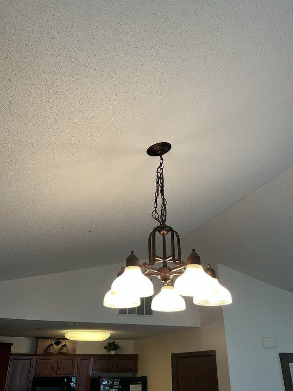 Arrived on-site and conducted assessment for ceiling fan installation to replace existing five-light chandelier fixture with bronze finish and frosted glass shades. Evaluated electrical box support requirements, switch configuration, and clearance specifications for proposed ceiling fan installation in room with vaulted ceiling. Provided detailed estimate for removal of current pendant-style lighting fixture and installation of customer-supplied ceiling fan, including necessary electrical connections and mounting hardware requirements.