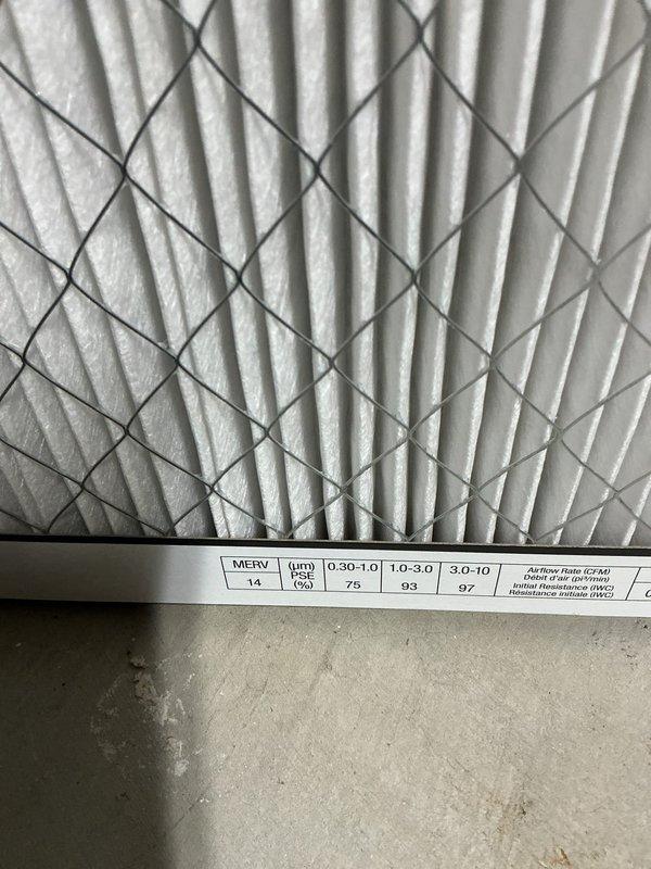 Responded to service call for water leaking from furnace and no cooling issue. Upon inspection, found unit was low on refrigerant. Inspected MERV 14 air filter showing proper installation with diagonal wire mesh support structure. Evaluated complete HVAC system including gray metal furnace unit with white PVC exhaust/intake venting configuration, wall-mounted control equipment, and air filtration system. Due to the age and overall condition of the equipment, provided estimates for repair options and recommended full system replacement as the most cost-effective long-term solution.