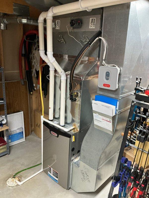 Responded to service call for water leaking from furnace and no cooling issue. Upon inspection, found unit was low on refrigerant. Inspected MERV 14 air filter showing proper installation with diagonal wire mesh support structure. Evaluated complete HVAC system including gray metal furnace unit with white PVC exhaust/intake venting configuration, wall-mounted control equipment, and air filtration system. Due to the age and overall condition of the equipment, provided estimates for repair options and recommended full system replacement as the most cost-effective long-term solution.