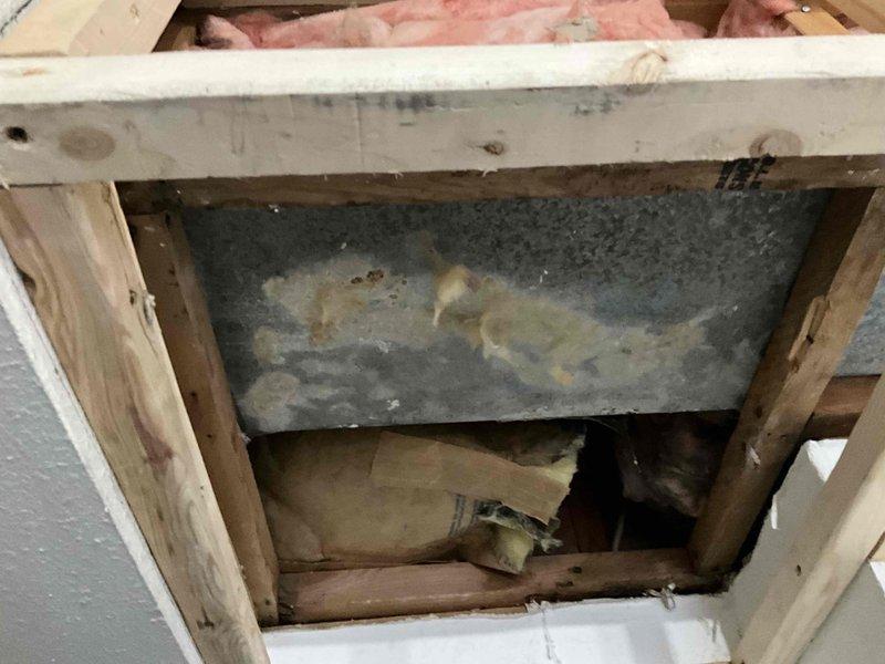 Responded to service call regarding damaged ceiling and exposed ductwork. Upon arrival, inspected wall cavity and discovered uninsulated metal ductwork with significant deterioration and moisture staining. Ceiling sheetrock showed water damage and structural compromise requiring replacement. Opened access point to assess full extent of ductwork condition, revealing corroded metal surfaces and inadequate insulation throughout the system. Documented existing conditions with photographs showing exposed copper piping, damaged fiberglass insulation, and compromised ductwork within structural framing. Provided estimate for complete ductwork insulation wrap to prevent future condensation issues and improve system efficiency.