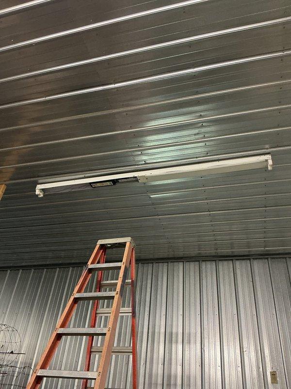 Completed electrical work on white metal shed building that was started a year prior. Diagnosed and replaced failed ballasts in two fluorescent light fixtures mounted on the corrugated metal ceiling. Both fixtures are now operational and providing proper illumination to the interior space.