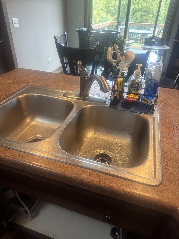 Arrived on-site and successfully replaced existing kitchen faucet with customer-supplied unit. Installed new chrome single-handle faucet with pull-down sprayer feature on double-basin stainless steel sink, ensuring proper mounting, water line connections, and leak-free operation upon completion.