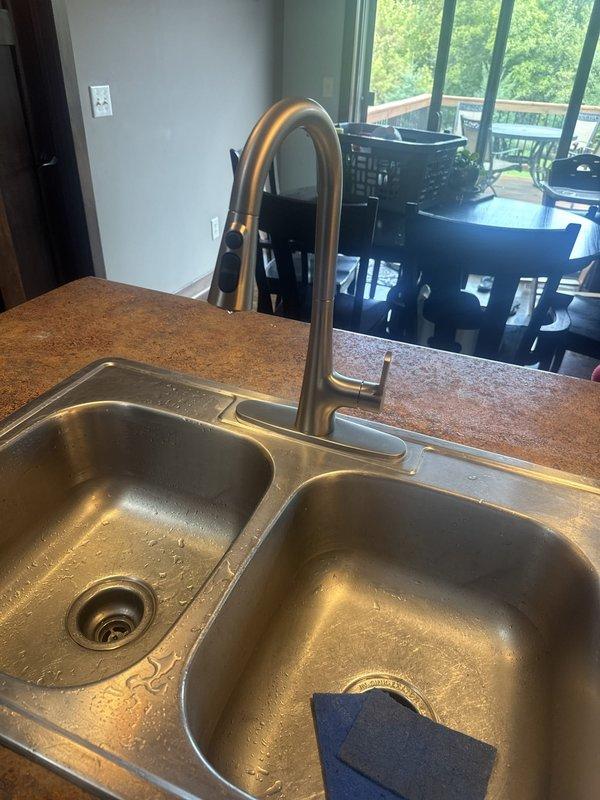 Arrived on-site and successfully replaced existing kitchen faucet with customer-supplied unit. Installed new chrome single-handle faucet with pull-down sprayer feature on double-basin stainless steel sink, ensuring proper mounting, water line connections, and leak-free operation upon completion.