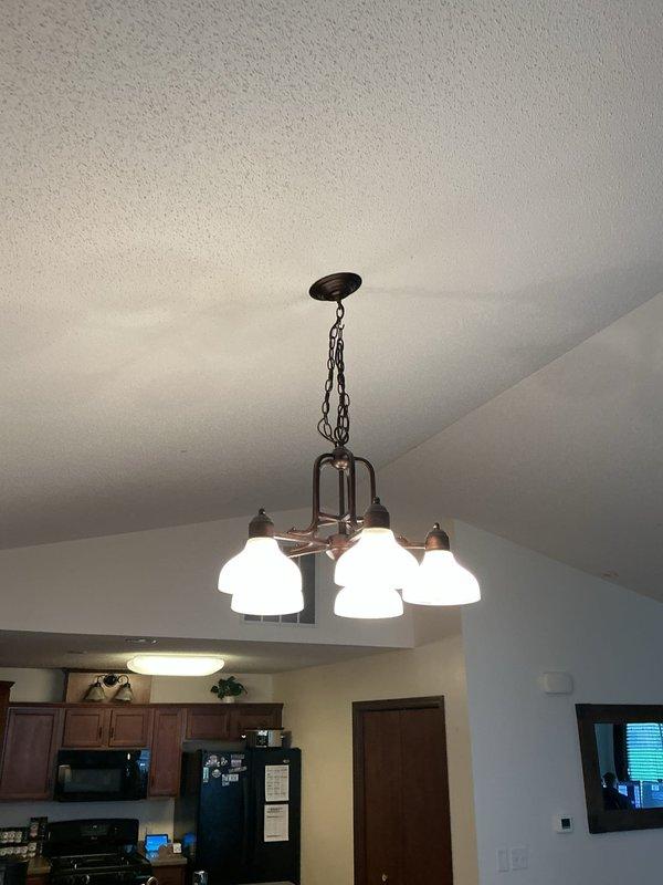 Installed customer-supplied ceiling fan with integrated light fixture in residential kitchen area, mounting unit to vaulted ceiling via downrod assembly. Verified proper electrical connections, tested fan operation across all speed settings and light functionality, and confirmed secure installation with pull chain controls operational.