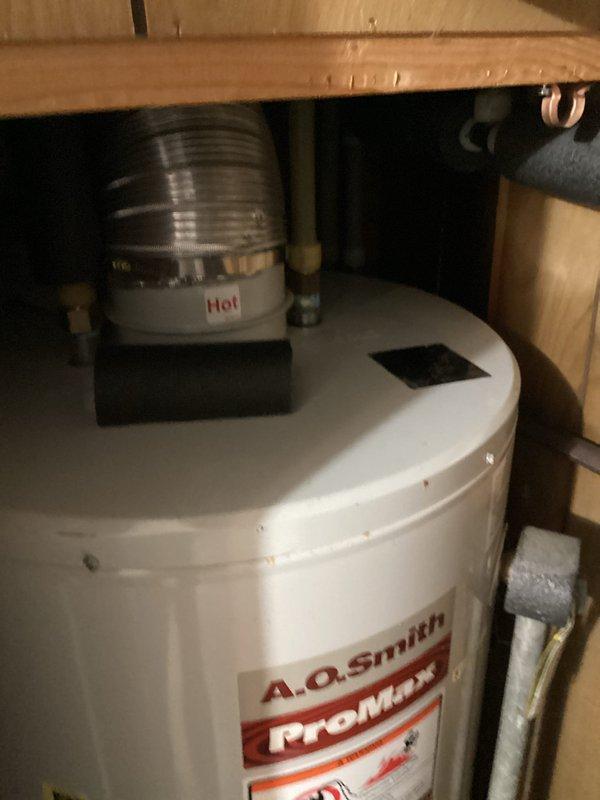 Responded to a water heater leak at the top of an A.O. Smith ProMax unit installed in a crawl space. Upon inspection, discovered the 3/4" cold inlet female adapter was cracked and actively leaking. Shut off water supply to prevent further damage. Removed the failed female adapter along with the affected pipe section. Installed new 3/4" female adapter and replacement pipe to the cold water inlet connection. Restored water supply and tested system operation. Verified all connections were secure with no leaks present and confirmed water heater returned to normal function.