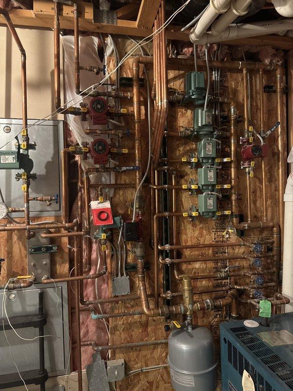 Responded to callback for ongoing boiler and in-floor heating issues. Diagnosed ghost flow condition in craft room zone caused by missing zone valve, resulting in unintended heat delivery when basement zone calls for heat. Documented existing multi-zone hydronic heating manifold system with multiple circulators and zone controls. Provided estimate for piping modifications and installation of additional zone valve to isolate craft room zone and eliminate cross-flow issue.