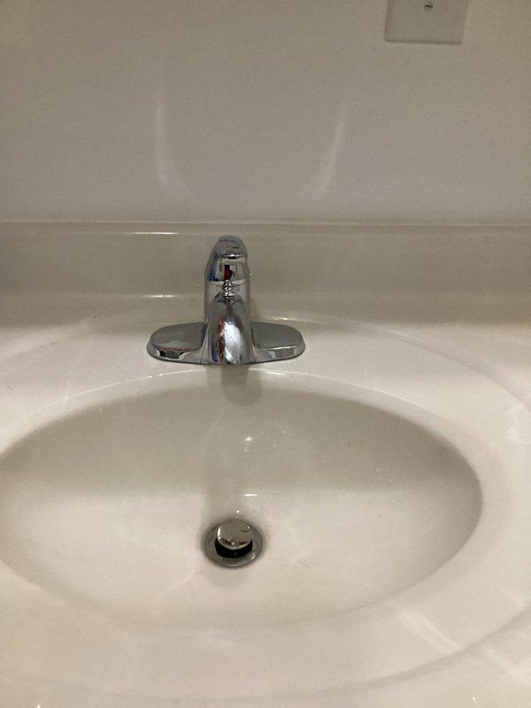 Responded to water leak under bathroom sink caused by cracked plastic component in the pop-up drain assembly. Removed existing lavatory faucet from basement bathroom and installed customer-provided chrome single-handle faucet with lever operation. Completed all supply line connections, installed pop-up drain assembly, and tested system under full water pressure. Verified proper operation of faucet handle, spout flow, and drain stopper mechanism with no leaks detected at supply connections or drain assembly.