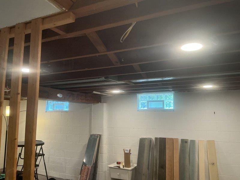 Installed seven recessed wafer lights in unfinished basement with exposed ceiling joists. Rerouted existing electrical wiring from under floor joists to run properly between joists to allow for future ceiling installation. Provided estimate for adding dedicated outlet under kitchen sink for garbage disposal.
