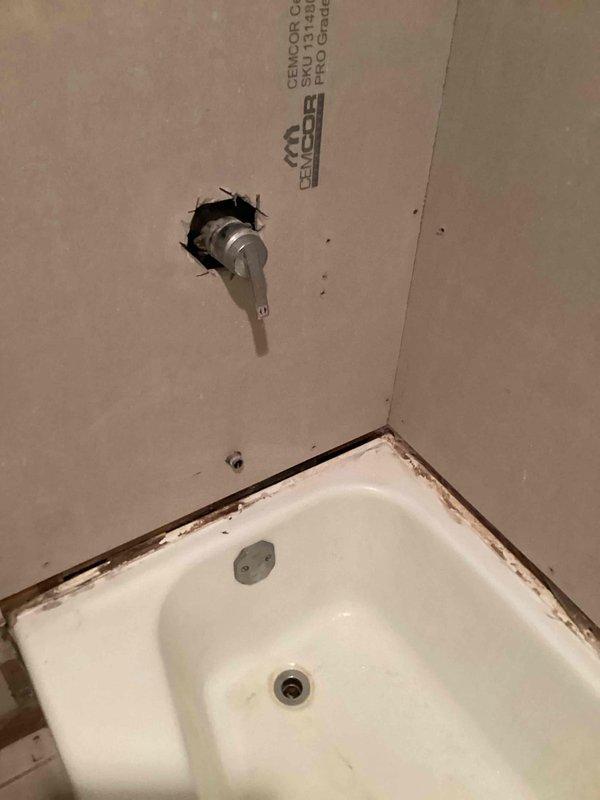 Provided estimate for bathroom shower fixture replacement including installation of customer-provided trim kit, handle, tub spout, and shower head. Assessment included replacing existing faucet with new valve assembly and extending water spout to accommodate updated fixture configuration. Documentation photos captured existing conditions showing tub-to-wall interface with visible staining and in-progress valve installation through wall penetration.