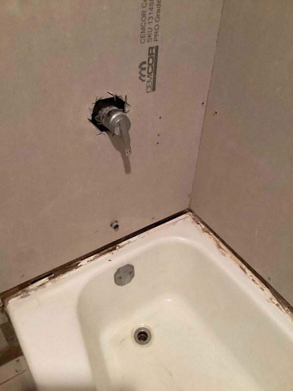 Provided estimate for bathroom shower fixture replacement including installation of customer-provided trim kit, handle, tub spout, and shower head. Assessment included replacing existing faucet with new valve assembly and extending water spout to accommodate updated fixture configuration. Documentation photos captured existing conditions showing tub-to-wall interface with visible staining and in-progress valve installation through wall penetration.