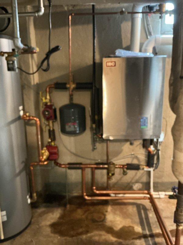 Responded to no hot water complaint and diagnosed low water pressure issue on IBC wall-mounted boiler system. Adjusted and increased system water pressure to restore proper operation of the hydronic heating unit. Verified hot water restoration and confirmed all valves, pressure gauges, and copper piping connections functioning correctly after pressure adjustment.