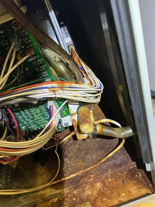 Responded to service call for furnace with reported water leakage issues ongoing since previous no-cooling call. Upon arrival, found standing water on ground near unit and confirmed active condensate leak causing extensive corrosion throughout system. Inspection revealed severely deteriorated burner assemblies, heavy rust accumulation on heat exchanger panels and base platform, and significant corrosion on internal metal surfaces and electrical components including control boards. Documented extensive damage with photographs showing compromised burners, corroded metal housing, rust-covered base pan, and deteriorated electrical control area. Due to advanced age of equipment and extent of water damage affecting critical components including heat exchanger, burners, and control systems, recommended full system replacement as most cost-effective solution. Provided repair and replacement options to address safety concerns and system reliability issues.