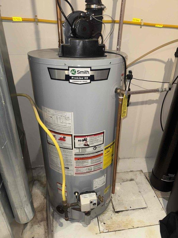 Responded to service call for leaking Grundfos booster pump that had previously leaked approximately one year ago. Upon inspection, confirmed active leak from booster pump assembly mounted above A.O. Smith ProLine-XE water heater. Determined pump was out of warranty and required replacement. Provided estimate for new booster pump installation and discussed system operation options with and without booster pump functionality. Performed water heater drain valve flush as part of maintenance service. Documented existing plumbing configuration including copper supply lines, PVC drain/vent piping, and current pump mounting arrangement with photographs for estimate preparation.