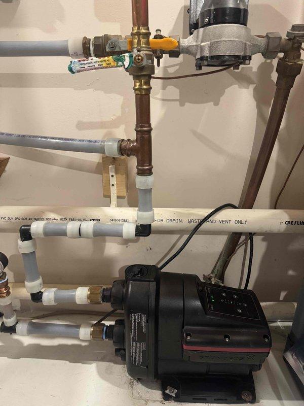 Responded to service call for leaking Grundfos booster pump that had previously leaked approximately one year ago. Upon inspection, confirmed active leak from booster pump assembly mounted above A.O. Smith ProLine-XE water heater. Determined pump was out of warranty and required replacement. Provided estimate for new booster pump installation and discussed system operation options with and without booster pump functionality. Performed water heater drain valve flush as part of maintenance service. Documented existing plumbing configuration including copper supply lines, PVC drain/vent piping, and current pump mounting arrangement with photographs for estimate preparation.