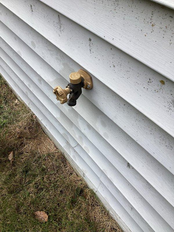 Diagnosed a leaking outdoor spigot (hose bib) and found the packing nut severely loose, allowing water to seep past the stem after use. Tightened the packing nut to restore the stem seal, then operated the faucet through multiple cycles to verify repair. No drips or leaks were present at the spigot with the valve in the closed position.