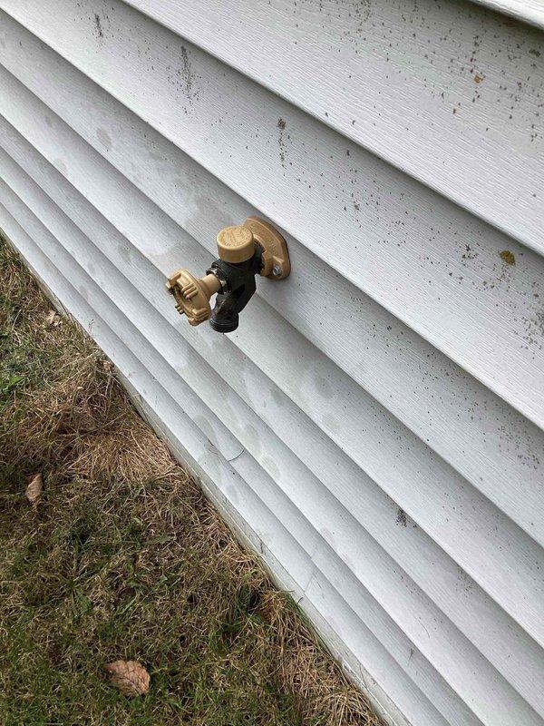 Diagnosed a leaking outdoor spigot (hose bib) and found the packing nut severely loose, allowing water to seep past the stem after use. Tightened the packing nut to restore the stem seal, then operated the faucet through multiple cycles to verify repair. No drips or leaks were present at the spigot with the valve in the closed position.