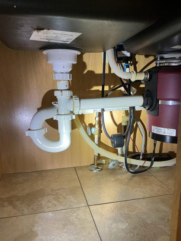 Installed a homeowner-supplied kitchen faucet and replaced the existing unit. Repiped the sink drain assembly, including the PVC tailpiece, tee, and P-trap connections to the garbage disposal and dishwasher drain line. Verified secure fittings and confirmed no leaks at the supply lines or drain connections.