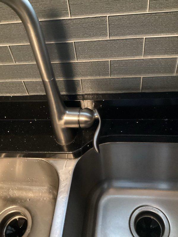 Diagnosed a loose kitchen faucet handle and found the cause to be a loose set screw securing the lever handle to the valve stem. Reseated the handle and tightened the set screw, then tested operation through full range of motion and confirmed the faucet functions properly with no replacement required.