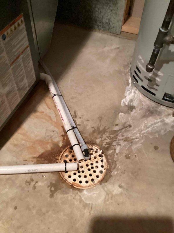 Responded to a callback on a previously installed water softener whose drain line had come loose and was discharging water onto the basement floor during the regeneration cycle. Cut back the excess drain line, installed a 90° fitting at the floor drain to terminate the line properly, and secured it to the condensate drain with zip ties to prevent movement and leakage.