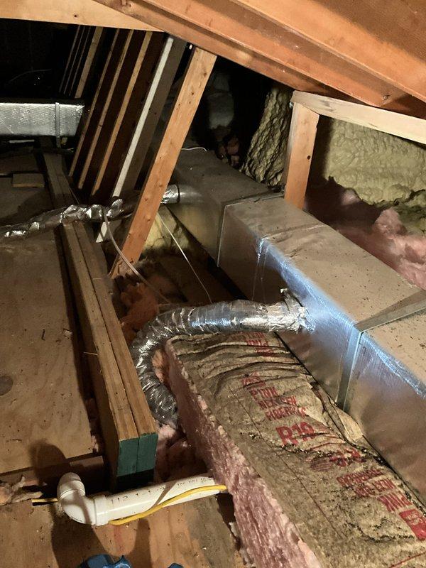 Oconomowoc, WI - Conducted site assessment and documentation for existing Spacepak HVAC system replacement in attic installation. Photographed current air handler unit with associated ductwork, flexible aluminum distribution lines, and existing spray foam and fiberglass insulation configuration. Documented equipment location, structural mounting with chain supports, electrical junction box positioning, and metal duct box connections for preparation of replacement system quote.