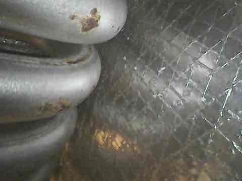 Responded to no cooling complaint on 20-year-old Armstrong Air package unit model 51HWC183A-3C. Upon inspection, found evidence of significant corrosion on evaporator coil components and refrigeration lines, indicating advanced age-related deterioration. Documented equipment condition with photographs showing rust and oxidation on critical components within the unit cabinet, which is likely contributing to system failure and refrigerant loss.