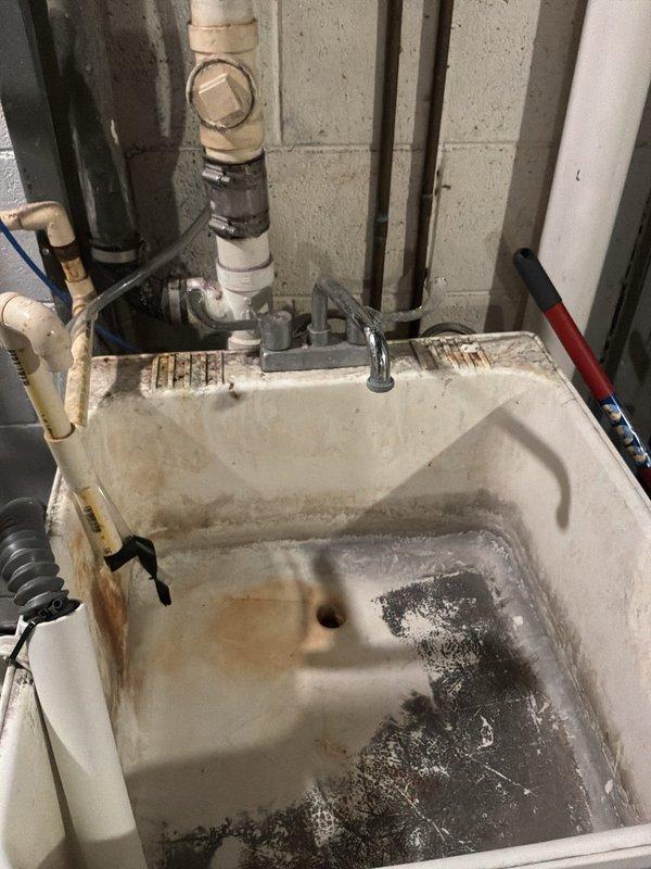 Completed PLUM Member Check Up on 1950 home with 20-30 minute availability window and text communication protocol. Verified and documented 15-year-old GE water heater (Model: GG50T06PVT, Serial: GELN0311V09052, installed March 2011). Inspected utility sink showing heavy mineral deposits, staining, and accumulated debris in basin with functional drainage system and PVC plumbing connections. Examined Mansfield toilet tank internal components including PM 300 flapper valve assembly, float mechanism, and flush valve system in proper working condition. Documented all equipment conditions and plumbing fixtures through photographic record for member maintenance files.