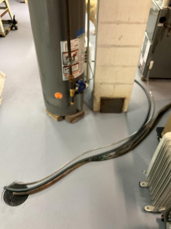 Conducted on-site estimate for HVAC system modifications in basement area. Evaluated existing furnace installation located beneath staircase to determine feasibility of relocating unit several feet to accommodate planned bathroom addition. Assessed current ductwork configuration including metallic supply ducts and flexible connections to identify optimal placement for additional return air vents throughout the space. Documented existing equipment layout including air handler position, ductwork routing, and clearance requirements. Photographed current HVAC system setup showing gray rectangular furnace with black flexible ductwork, overhead metallic duct runs, and surrounding basement infrastructure to support modification proposal.