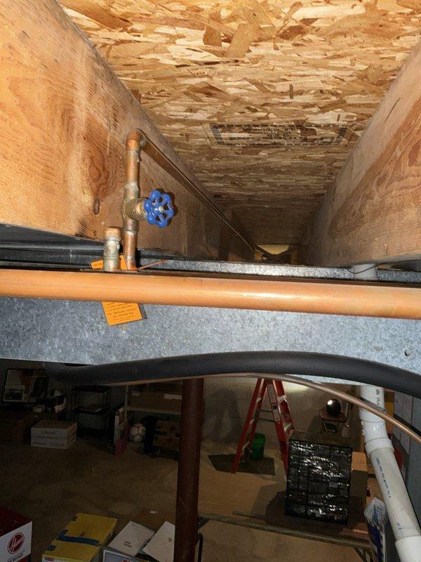 Responded to a plumbing emergency involving a frozen and ruptured backyard spigot that caused significant water leakage in the basement. Upon inspection, identified freeze damage to the exterior hose bib which resulted in active water intrusion affecting basement ceiling joists and subfloor, with visible water staining and deterioration present. Assessed the affected area where copper supply lines and PEX tubing penetrate through the floor structure, documented the extent of water damage to wooden structural components, and verified the condition of the 9-year-old A.O. Smith GCR-40 water heater (Serial: 1646104016895) located in the basement to ensure no collateral damage from the leak.