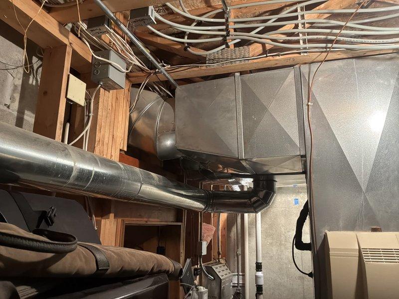 Responded to cooling concern in basement area where conditioned air was being delivered despite thermostat being in the off position. Inspected Armstrong Air furnace (Model G1D91AU100D20C-1A, 23 years old) and associated ductwork system serving the basement zone. Evaluated galvanized sheet metal plenum and flexible duct branches to identify which cooling equipment was actively serving the space and determined cause of unwanted air delivery when system should not be operating.