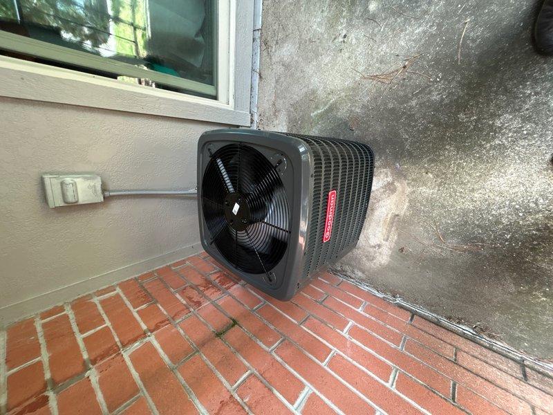 Successfully completed installation of complete HVAC system including Goodman GLXS3BN1810 air conditioning condenser unit, FirstCo 19HXS0002UCV000AAF fan coil air handler, and Honeywell TH4210U2002 thermostat. Condenser unit positioned on brick paver pad against exterior wall with proper clearances maintained, electrical connections completed and secured at junction box, and refrigerant lines installed between outdoor and indoor units. All equipment verified operational, system tested for proper cooling cycle, and thermostat programmed for optimal performance.