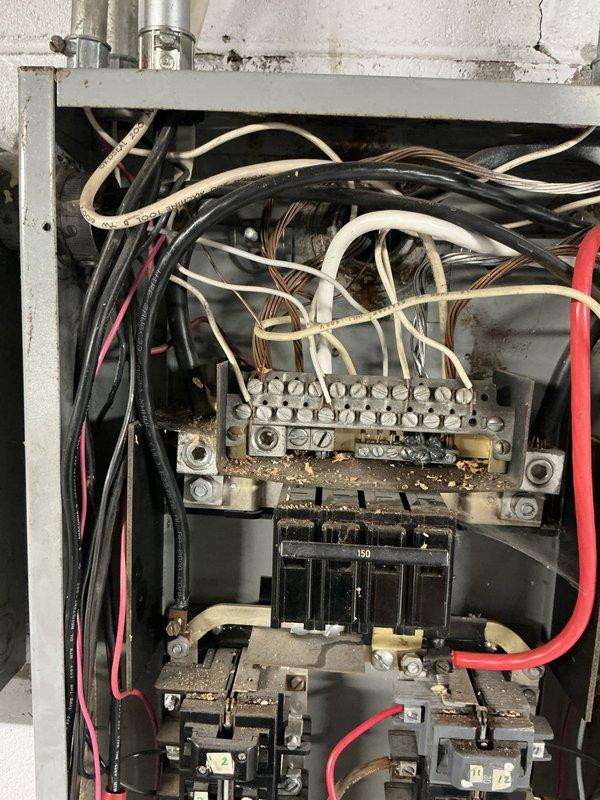 Conducted comprehensive site evaluation for standby generator installation at residential property. Performed detailed assessment of existing electrical infrastructure, including main service panel located in basement utility area. Documented current electrical system configuration, panel capacity, and available breaker spaces to determine generator interconnection requirements. Evaluated main service panel condition, noting significant corrosion, rust accumulation, and debris buildup on bus bar connections and interior components, indicating potential need for panel replacement or upgrade prior to generator integration. Assessed wire routing pathways, conduit locations, and transfer switch placement options in basement area near existing electrical equipment. Photographed electrical panel configuration showing 150-amp service with multiple circuit connections and aging wire insulation. Reviewed available space for automatic transfer switch installation and determined optimal location 