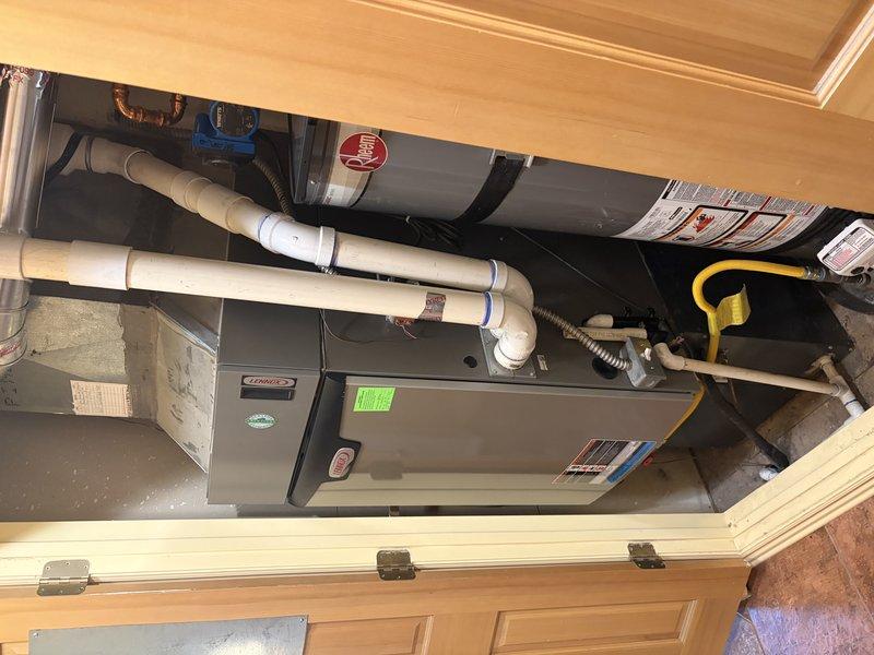 Responded to service call for Lennox furnace blower making abnormal noise during operation. Upon arrival, performed visual inspection of furnace unit located in interior mechanical closet. Conducted operational test of blower assembly while system was running. Identified source of noise as deteriorated blower motor mounting hardware showing signs of corrosion and wear at connection points. Inspected motor bearings, blower wheel balance, and mounting brackets for mechanical defects. Found corrosion present on mounting bolt assembly causing vibration and rattling during blower operation. Verified all electrical connections, refrigerant lines, and PVC venting pipes secure and properly installed. Confirmed furnace and AC system functioning within normal parameters despite noise issue. Documented condition with photographic evidence showing corroded mounting hardware and overall system configuration. Provided recommendations for blower motor mounting hardware replacement to eliminate noise 