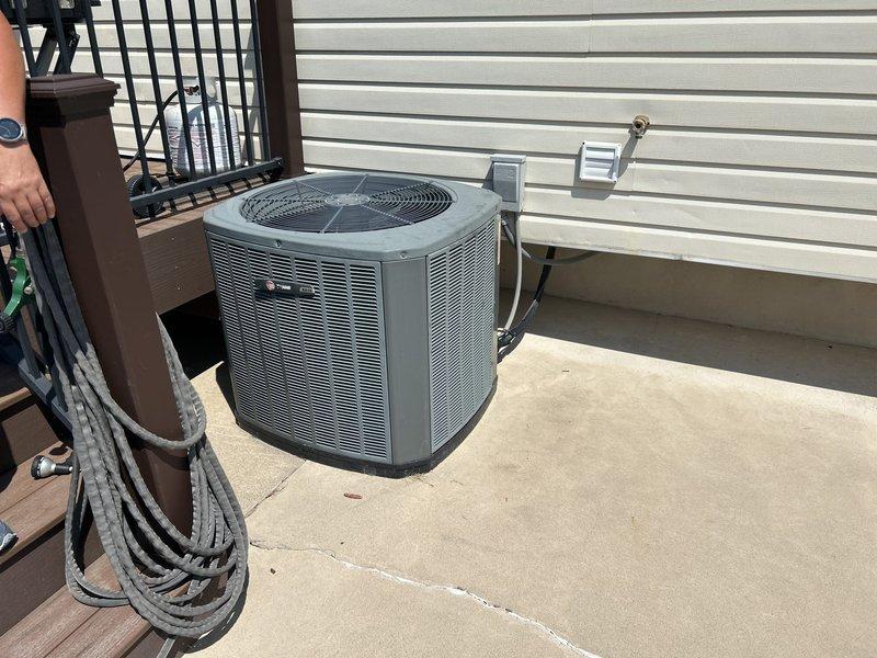 Conducted comprehensive HVAC system evaluation for 15-year-old residential heating and cooling equipment experiencing inadequate cooling performance and refrigerant loss. Assessed outdoor condensing unit, indoor Trane furnace, and associated ductwork and refrigerant lines to determine system viability and provided replacement equipment estimate. Documented existing equipment condition through photographic survey showing outdoor condenser unit on concrete pad with electrical disconnect, indoor furnace installation in mechanical closet with copper refrigerant lines and ductwork, and adjacent water heater for complete system assessment.