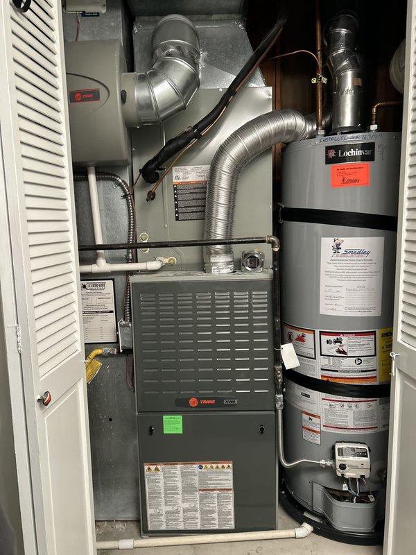 Conducted comprehensive HVAC system evaluation for 15-year-old residential heating and cooling equipment experiencing inadequate cooling performance and refrigerant loss. Assessed outdoor condensing unit, indoor Trane furnace, and associated ductwork and refrigerant lines to determine system viability and provided replacement equipment estimate. Documented existing equipment condition through photographic survey showing outdoor condenser unit on concrete pad with electrical disconnect, indoor furnace installation in mechanical closet with copper refrigerant lines and ductwork, and adjacent water heater for complete system assessment.