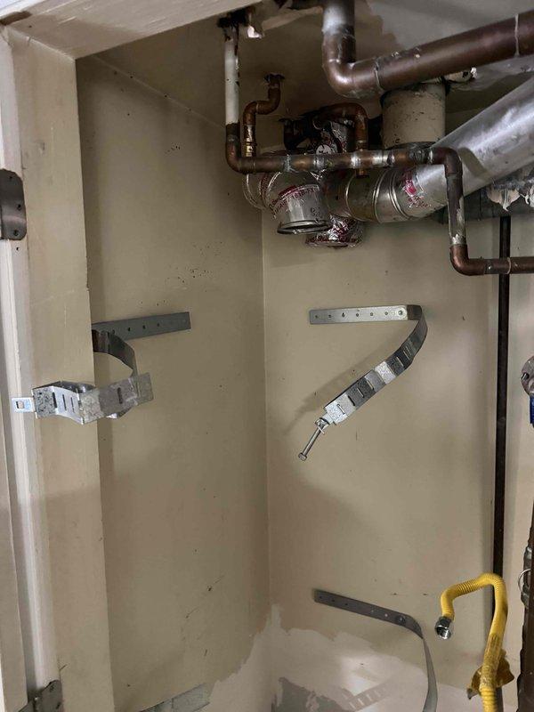 Conducted assessment of existing fireplace system in living room of rental property. Unit is extremely aged with unknown service history and currently non-operational. Documented existing installation measuring approximately 3 feet deep by 30 inches wide. Photographed current mechanical systems and plumbing infrastructure to evaluate replacement requirements. Noted existing copper piping, valve assemblies, and gas line connections in utility area. Observed water staining on flooring near plumbing components, indicating potential moisture concerns requiring attention during replacement. Provided estimate for replacement unit suitable for rental property application, focusing on cost-effective, reliable operation rather than high-end features per owner specifications.