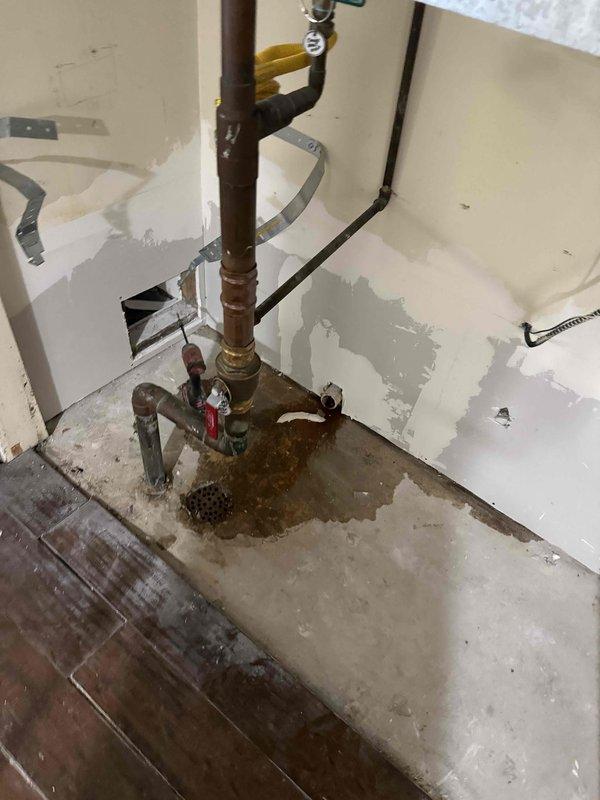 Conducted assessment of existing fireplace system in living room of rental property. Unit is extremely aged with unknown service history and currently non-operational. Documented existing installation measuring approximately 3 feet deep by 30 inches wide. Photographed current mechanical systems and plumbing infrastructure to evaluate replacement requirements. Noted existing copper piping, valve assemblies, and gas line connections in utility area. Observed water staining on flooring near plumbing components, indicating potential moisture concerns requiring attention during replacement. Provided estimate for replacement unit suitable for rental property application, focusing on cost-effective, reliable operation rather than high-end features per owner specifications.