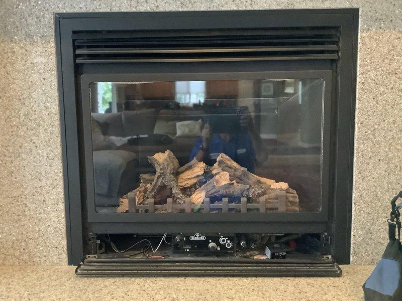 Performed diagnostic inspection on built-in gas fireplace unit with ceramic log set and glass viewing panel. Assessed fireplace components including burner assembly, control panel with multiple knobs, and ventilation system to provide updated repair estimates for previously identified issues. Documented equipment model information and current operating condition of main floor fireplace system.