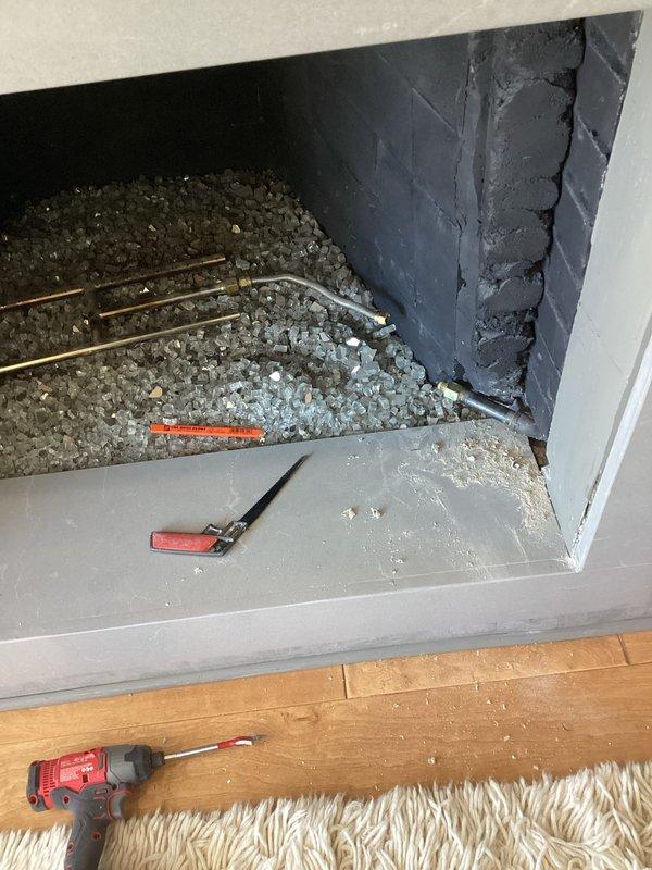 Responded to emergency no-gas situation where gas company had shut off main supply due to leak at fireplace valve in living room. Accessed fireplace gas line through wall opening, located failed valve assembly behind brick exterior wall, and replaced defective valve with new unit. Pressure tested gas line connections to verify leak elimination, restoring gas service to entire home including water heater and all gas appliances.