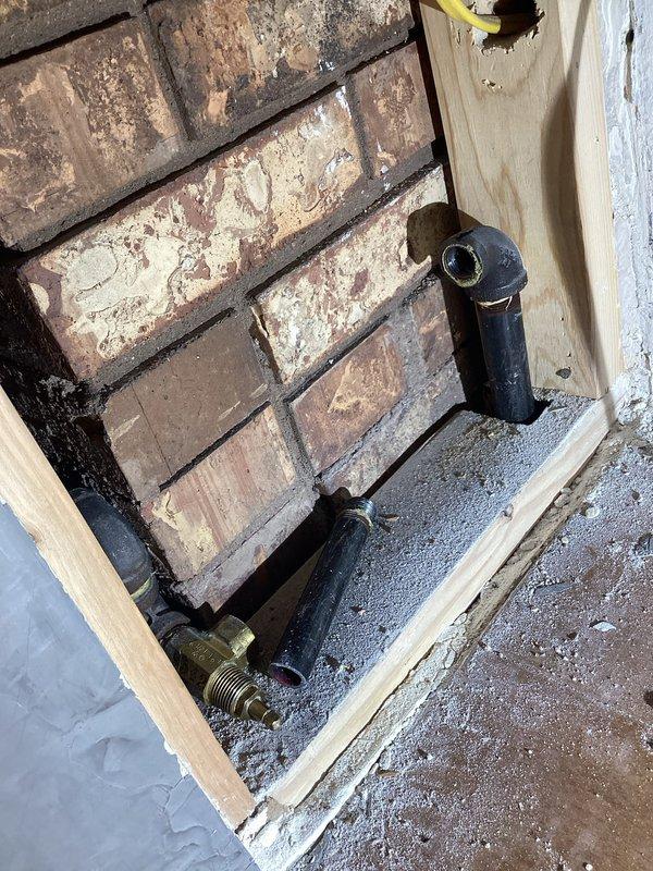 Responded to emergency no-gas situation where gas company had shut off main supply due to leak at fireplace valve in living room. Accessed fireplace gas line through wall opening, located failed valve assembly behind brick exterior wall, and replaced defective valve with new unit. Pressure tested gas line connections to verify leak elimination, restoring gas service to entire home including water heater and all gas appliances.